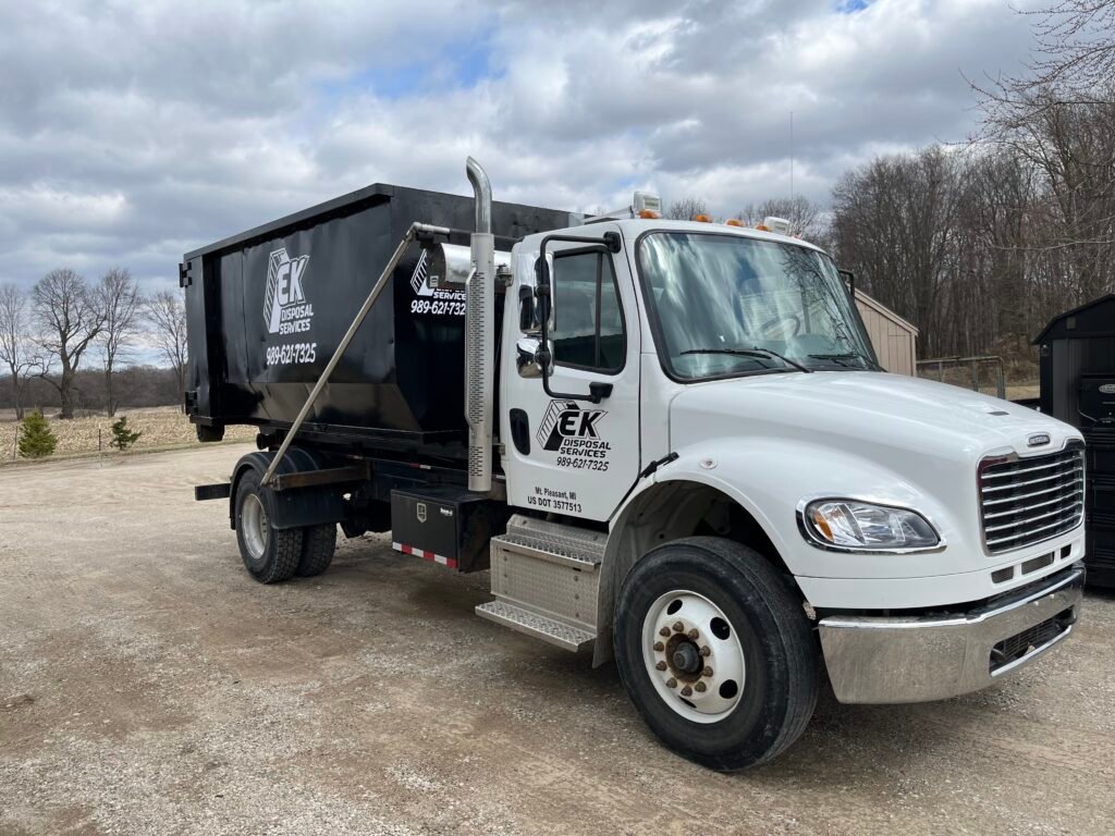 EK Disposal Services roll-off truck delivering a dumpster