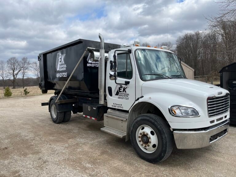 EK Disposal Services roll-off truck delivering a dumpster
